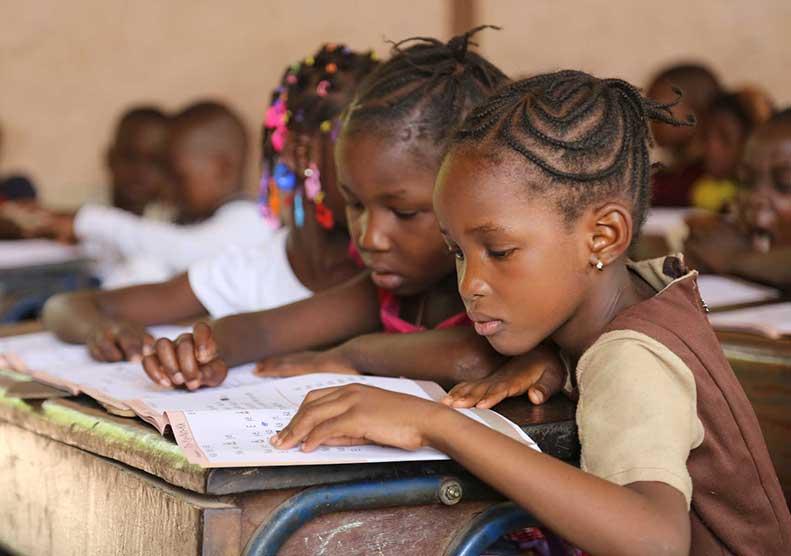 Children reading together at classroom desks.